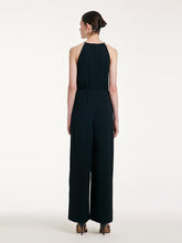 A lady wears a halter top and black pants.